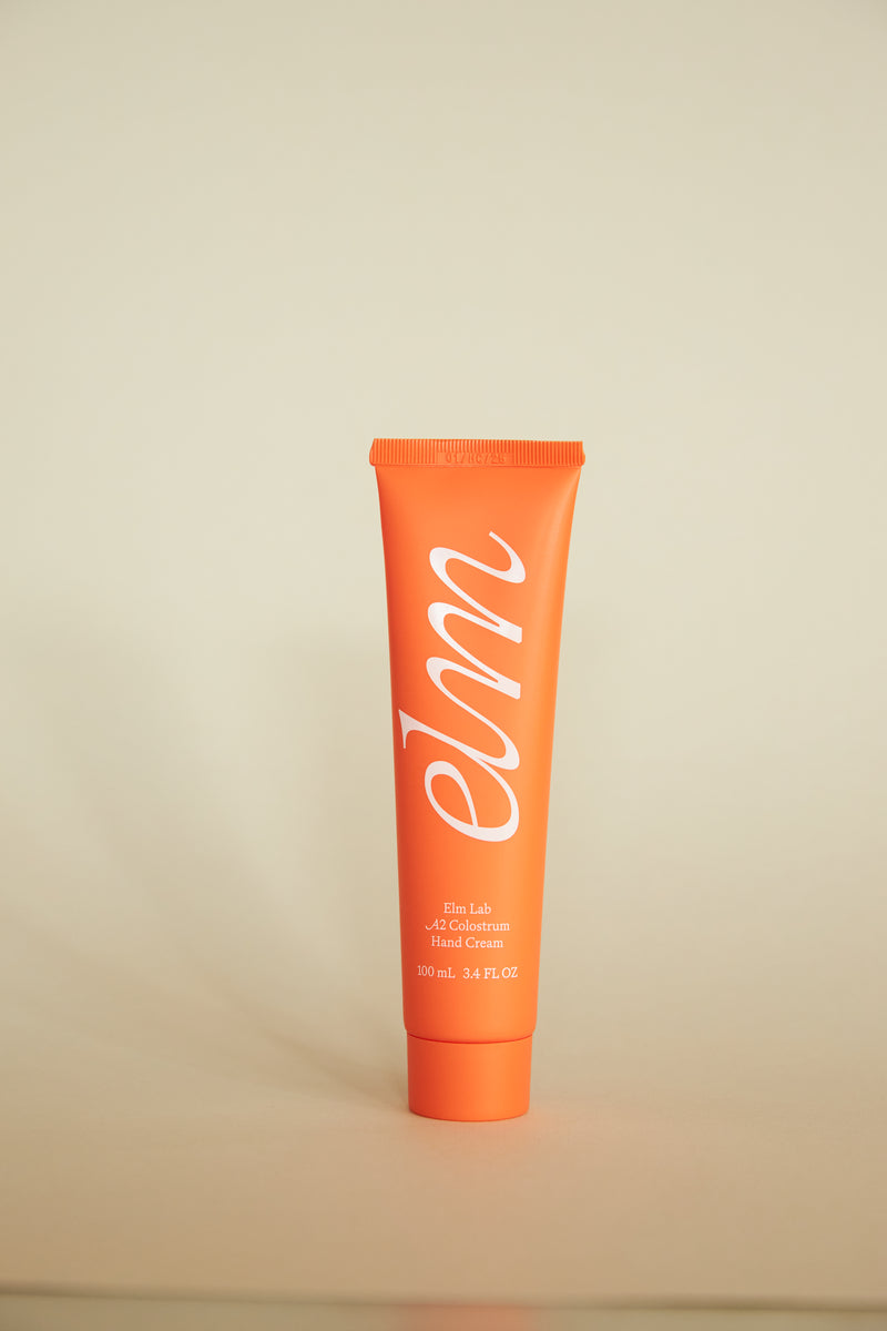 Orange tube of elm hand cream on a beige background